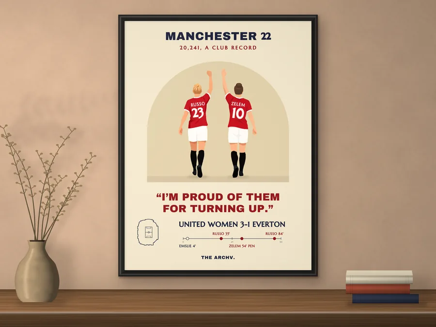 Framed poster on a wall: Manchester United Women's 3-1 win over Everton at Old Trafford, 2022, two players seen from behind.