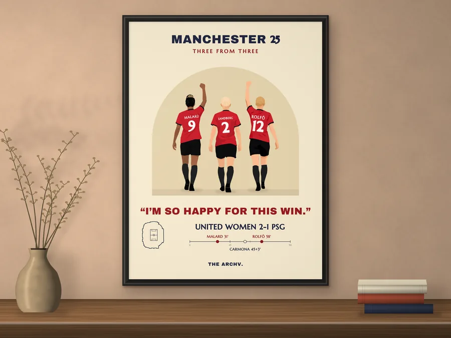 Framed poster on a wall: Manchester United Women's 2-1 win over Paris Saint-Germain at Old Trafford, November 2025, three players seen from behind.